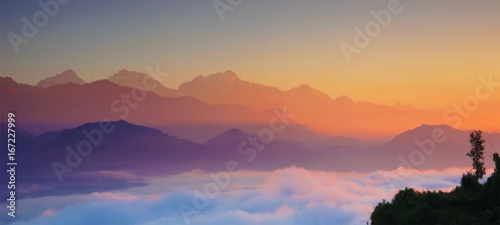 Himalaya mountains at dawn, with fog and clouds. Natural background, blurred. Horizontal panoramic view.