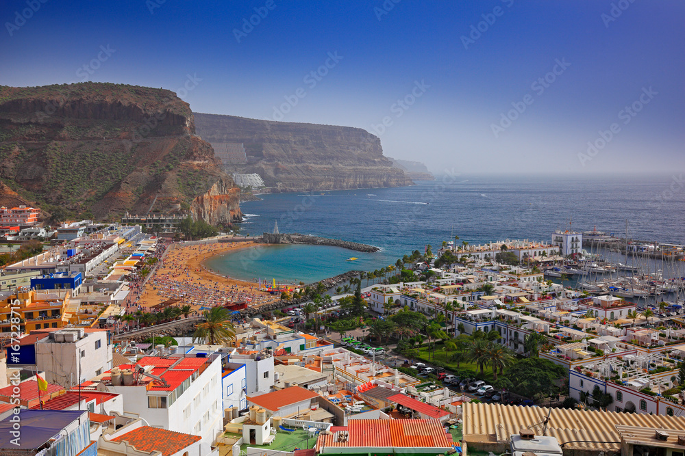 Puerto Mogan, Gran Canaria, Holiday in Canary Island, Spain, Europe. Small town on the south coast. Summer in Puerto Mogan, blue sky. Mountain with sea. Red roof houses in clean town