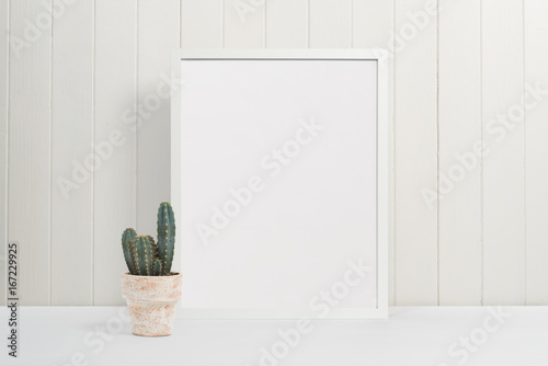 White picture frame on white background with cactus plant in plant pot