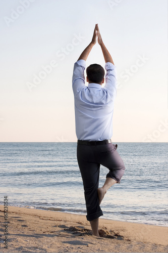 Businessman doing yoga on the beach  photo