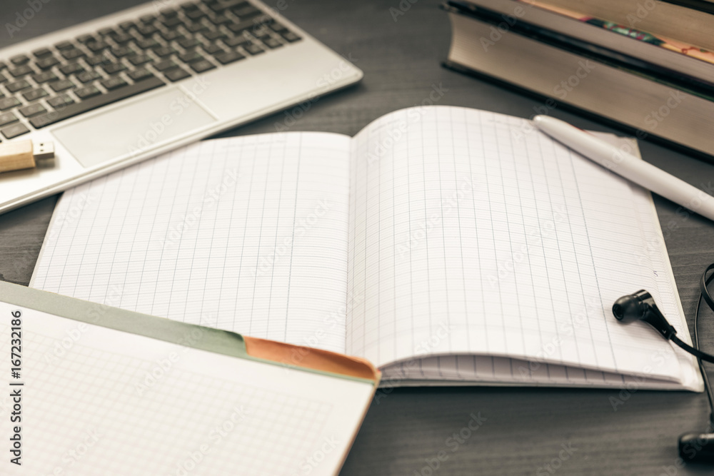 Office workplace with open laptop. Workspace of business man or student. notebooks, pen, books, earphones on grey wooden desk Office workplace with open laptop. Workspace of business man or student. notebooks, pen, books, earphones on grey wooden desk