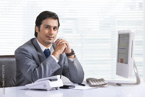 Portrait of confident young businessman sitting at office desk