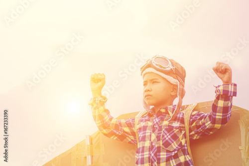 Child pretend to be pilot. Kid having fun at outdoor.He used paper to make wings. Summer vacation and travel concept.