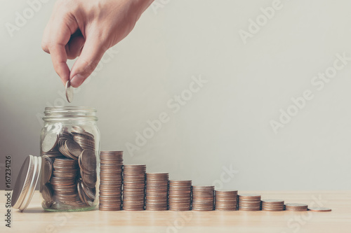Hand of male or female putting coins in jar with money stack step growing growth saving money, Concept finance business investment photo