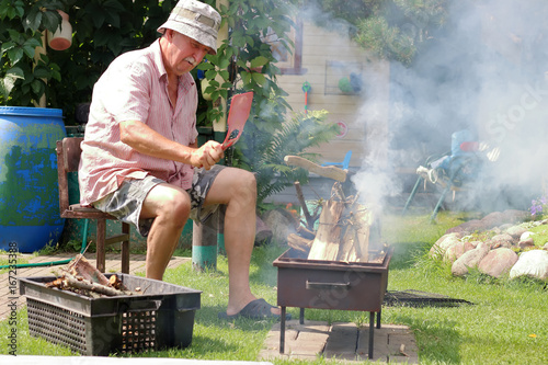 Senior man lights the fire in the garden