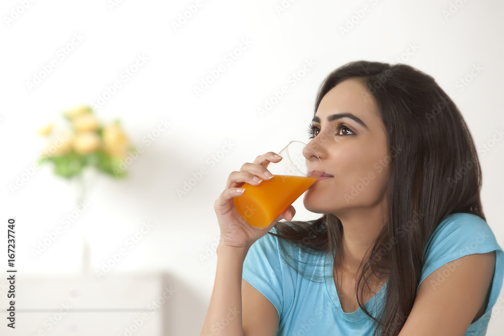Thoughtful young woman drinking orange juice at home Thoughtful young woman drinking orange juice at home