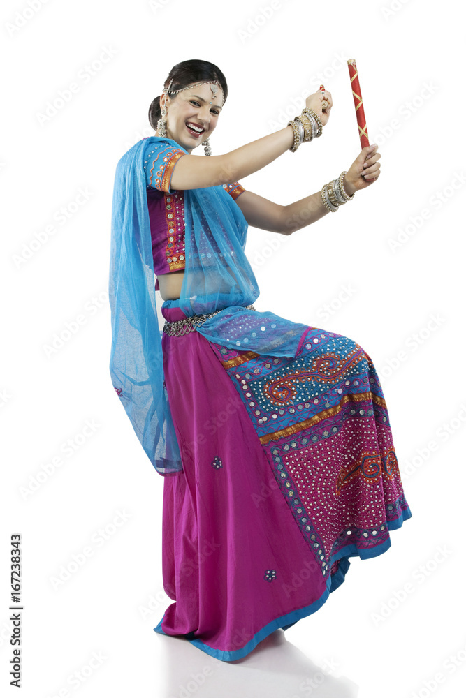 Portrait of young woman in chaniya choli performing Dandiya Raas over white  background Stock Photo | Adobe Stock