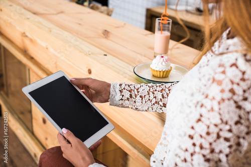 cropped shot of young woman using digital tablet with blank screen while sitting in cafe