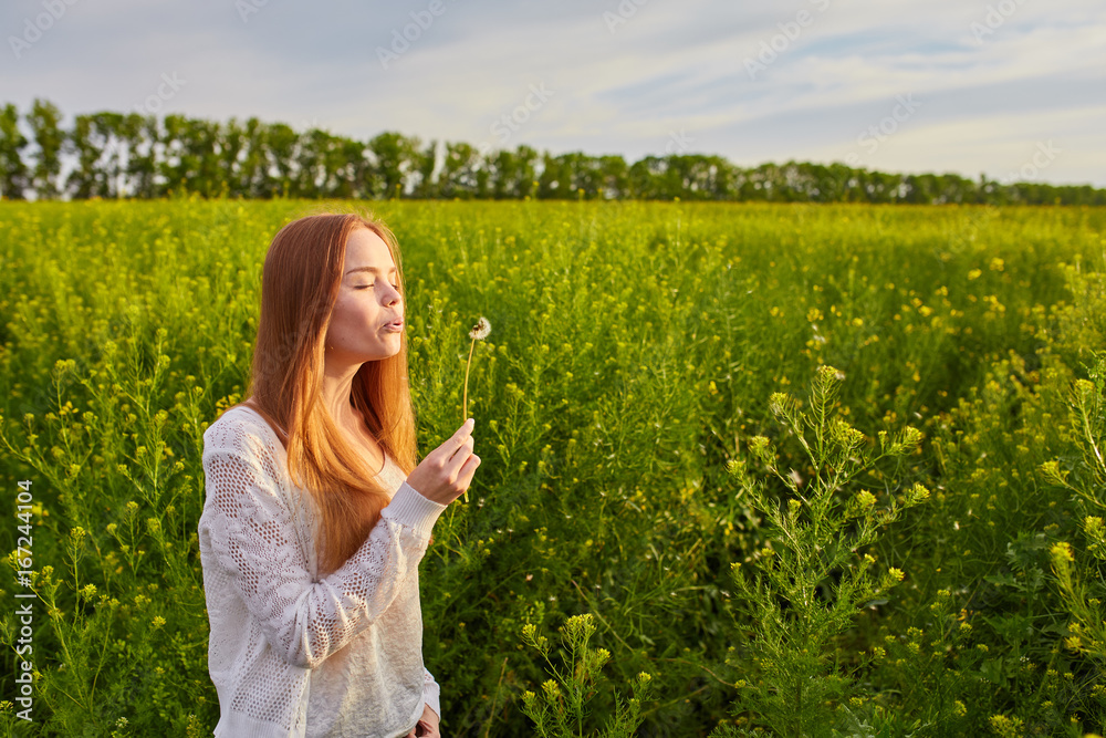 redheaded teen girl blowing on dandelions redheaded teen girl blowing on dandelions