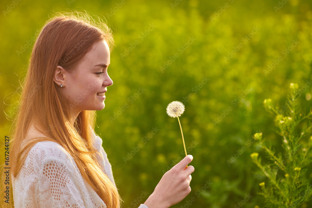 redheaded teen girl blowing on dandelions redheaded teen girl blowing on dandelions