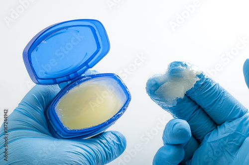 Proctological exam and rectal examination concept with a closeup on the hands of a proctologist getting ready for DRE by lubricating his latex gloves with petroleum jelly
