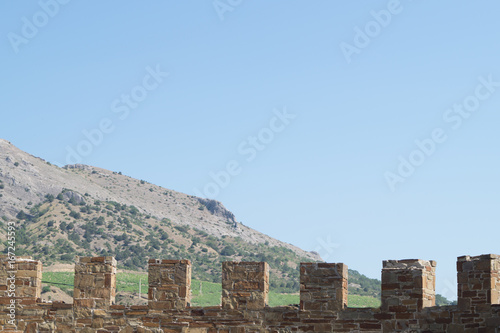 Old wall with battlement in Sudak fortress  Crimea. Mountain on the background.