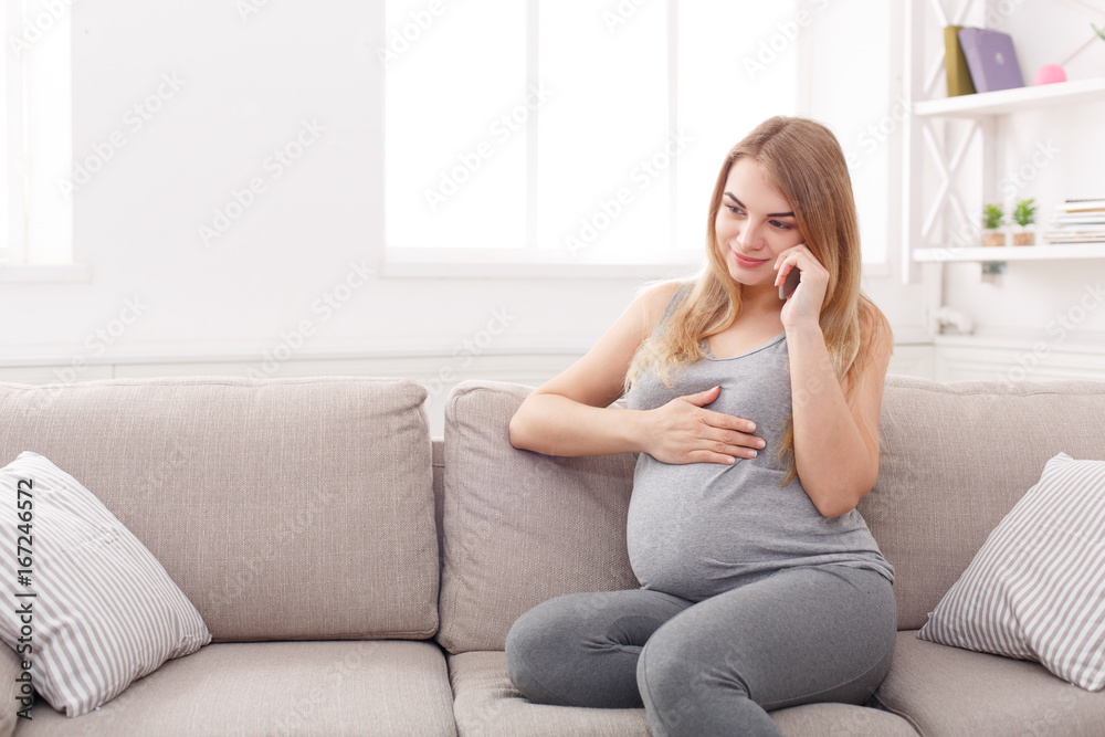 Smiling pregnant woman talking on her smartphone Smiling pregnant woman talking on her smartphone