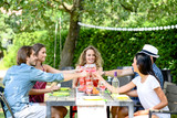 group of friends having fun picnic lunch party outdoor in backyard during summer holiday vacation