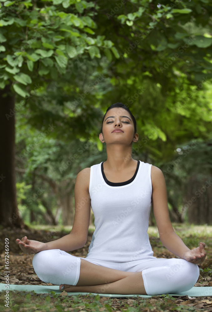 Young woman in lotus position meditating in a park Young woman in lotus position meditating in a park