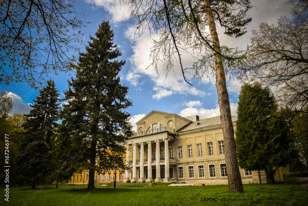 Nice view on Sukhanovo palace in Moscow region and public park. Antique mansion 18-19 century in classicism style. Beautiful landscape with old manor, lawn, sky and trees for wallpapers, prints.