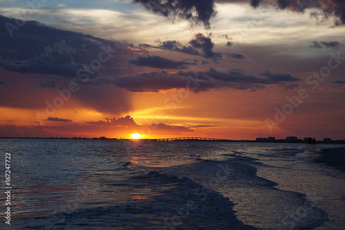 A colorful orange sunset against the waves of the ocean in Ft.Myers Beach, Florida.