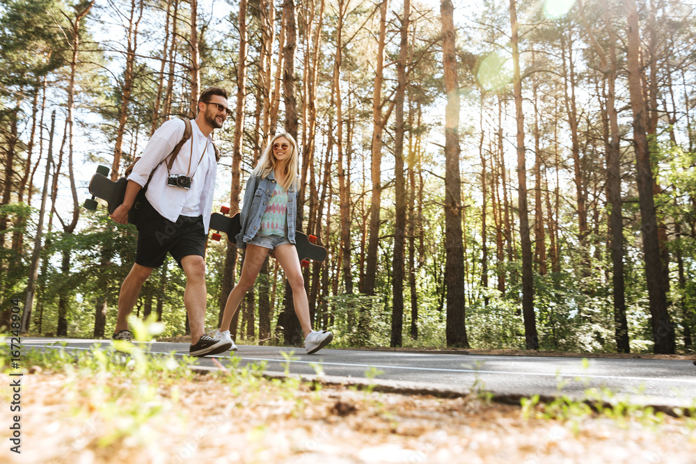 Loving couple walking with skateboards outdoors. Loving couple walking with skateboards outdoors.