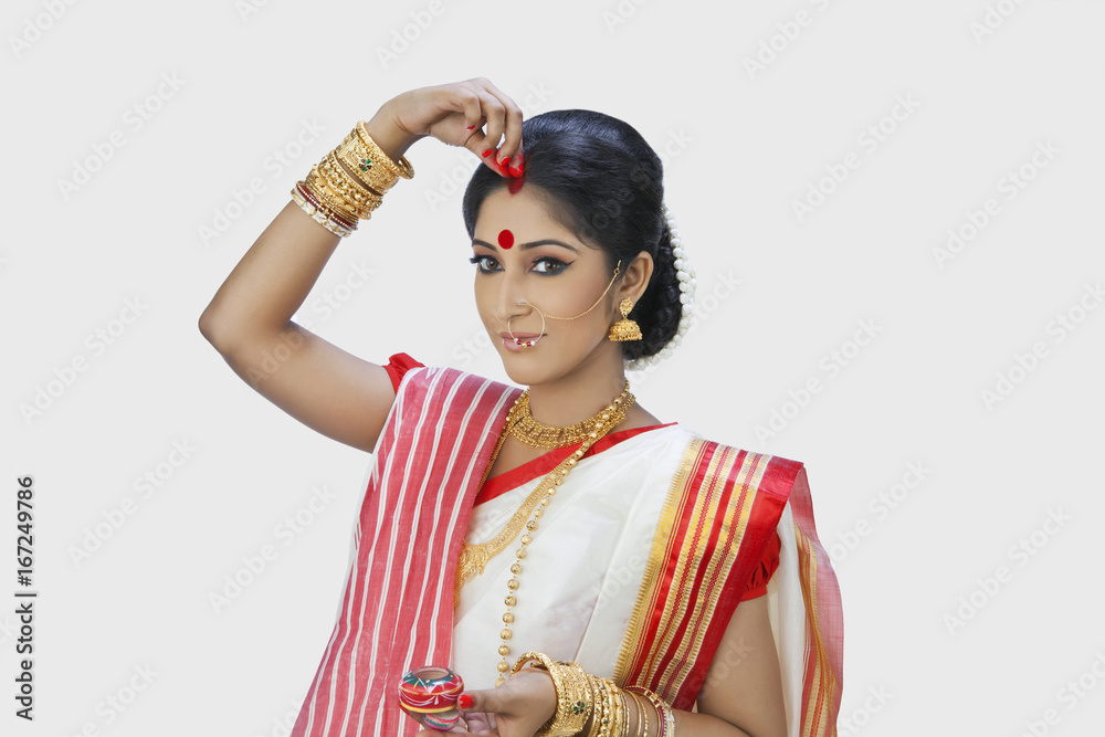 Bengali woman putting sindoor on her forehead