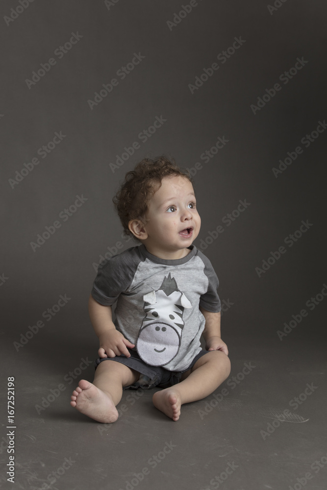 Small boy sitting on grey seamless background Small boy sitting on grey seamless background