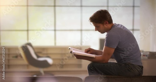 Young man reading a book on a couch