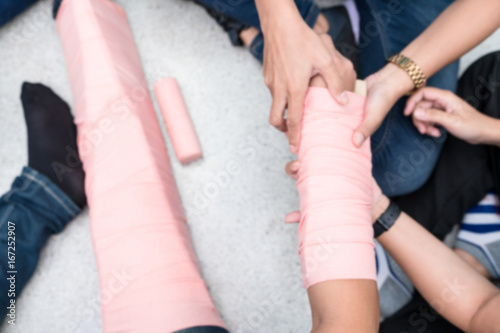At First Aid Training Classroom  Students are trying to splint the arm of a patient s broken arm incident with cardboard and elastic bandage.