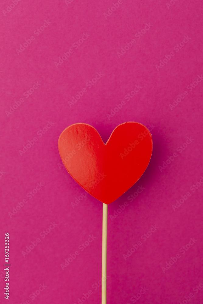 Paper heart on a stick over a bright pink background Paper heart on a stick over a bright pink background