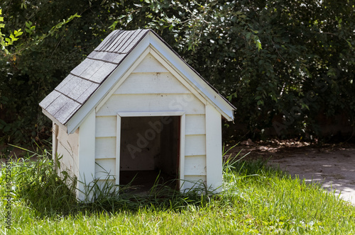White wooden doghouse on a house backyard photo