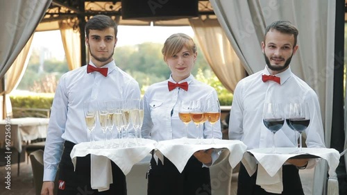 Waiters greet guests with alcoholic drinks. Champagne, red, white wine on trays photo