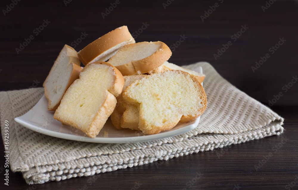 Crispy buns in white dish on wooden dark background