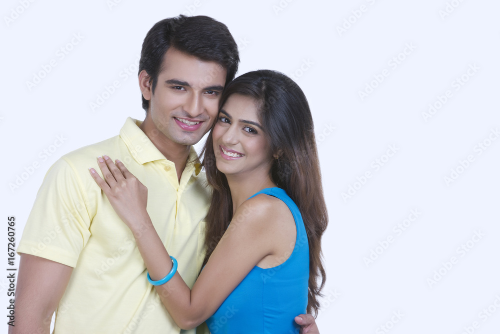Portrait of happy young couple embracing over white background