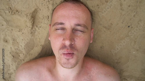 top view of young man inflating bubbles lying on the beach.