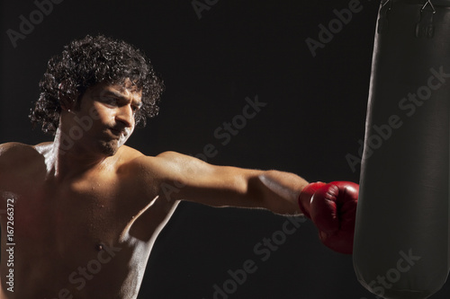 Boxer about to hit punching bag over black background  © IndiaPix