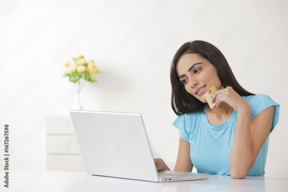 Beautiful young woman with credit card shopping online at home Beautiful young woman with credit card shopping online at home