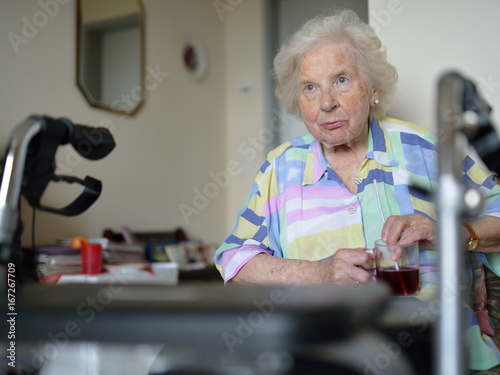 Eine an Parkinson-Demenz erkrankte ältere Patientin im Zimmer eines Pflegeheims. Krankheitsbedingt benötigt sie einen Strohhalm zum Trinken.