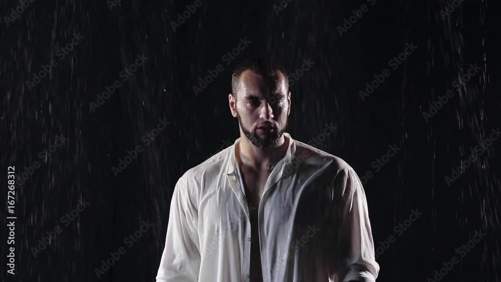 sad big man with big shoulders and a beard the night in the cold rain in wet clothes white. he bowed his head down