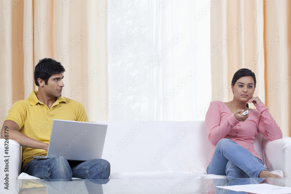 Man using laptop while looking at girlfriend Man using laptop while looking at girlfriend