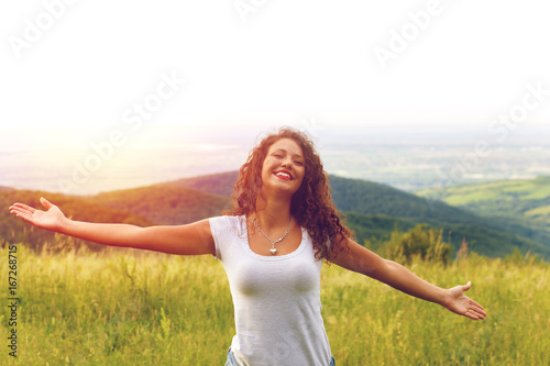 Portrait of a happy young woman on a viewpoint with her arms outstretched.