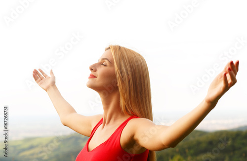 Portrait of a happy young woman on a viewpoint with her arms outstretched. photo