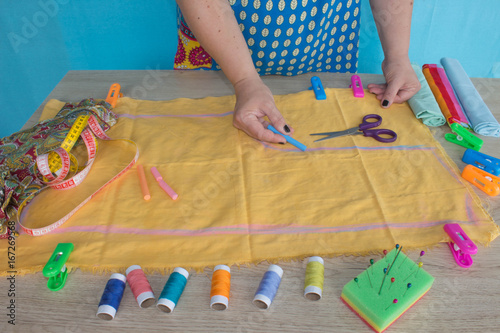 closeup of woman hands sewing yellow cloth outdoors photo