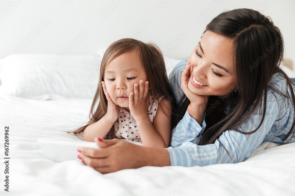 Amazing young woman with little daughter using mobile phone. Amazing young woman with little daughter using mobile phone.