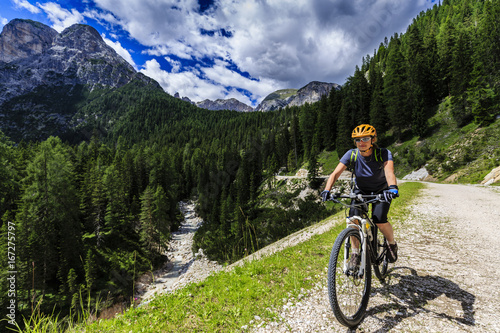 Mountain biking woman along river in Dolomites, Italy