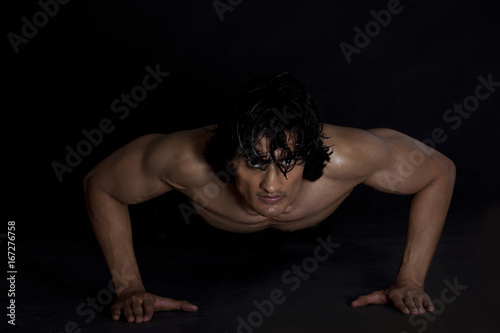 Portrait of young man exercising against black background 