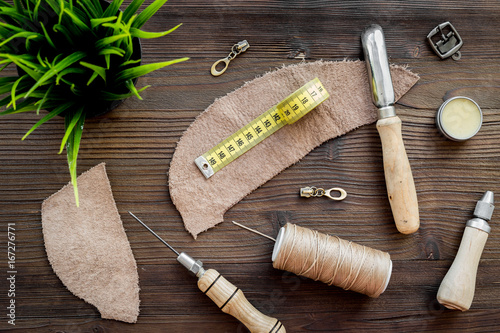 Leather craft workshop. Tools on dark wooden table background top view