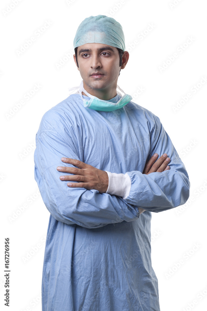 Thoughtful male surgeon with hands folded over white background Thoughtful male surgeon with hands folded over white background