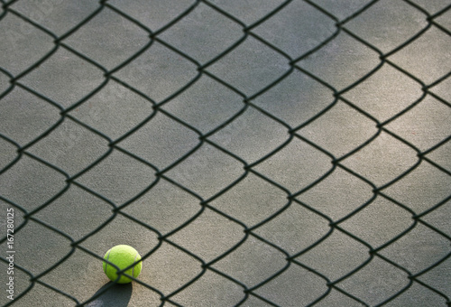 Shot of tennis ball lying on ground in front of net 