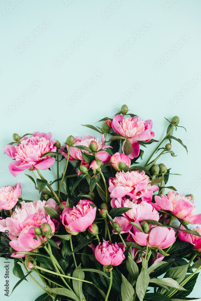 Beautiful pink peonies flowers bouquet on pale blue background. Flat lay, top view flowers pattern.
