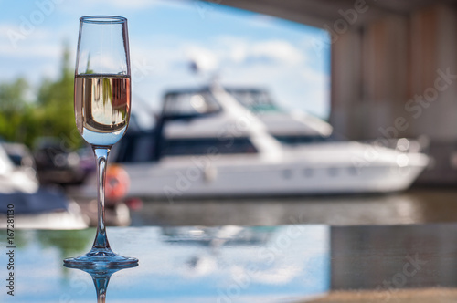 a glass of champagne in front of a white yacht