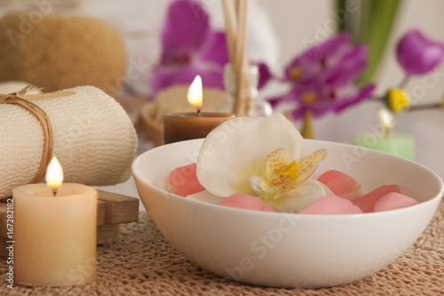 Flowers in a bowl with candles and bath scrub 