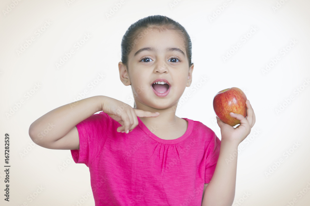 Portrait of shocked girl showing fresh apple against colored background Portrait of shocked girl showing fresh apple against colored background
